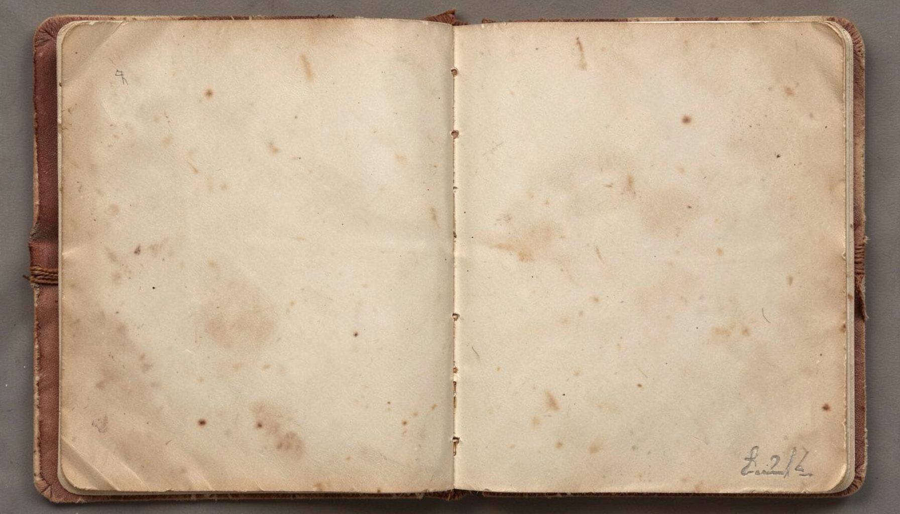 An aged open scrapbook page with faded brown tones, evoking history and remembrance