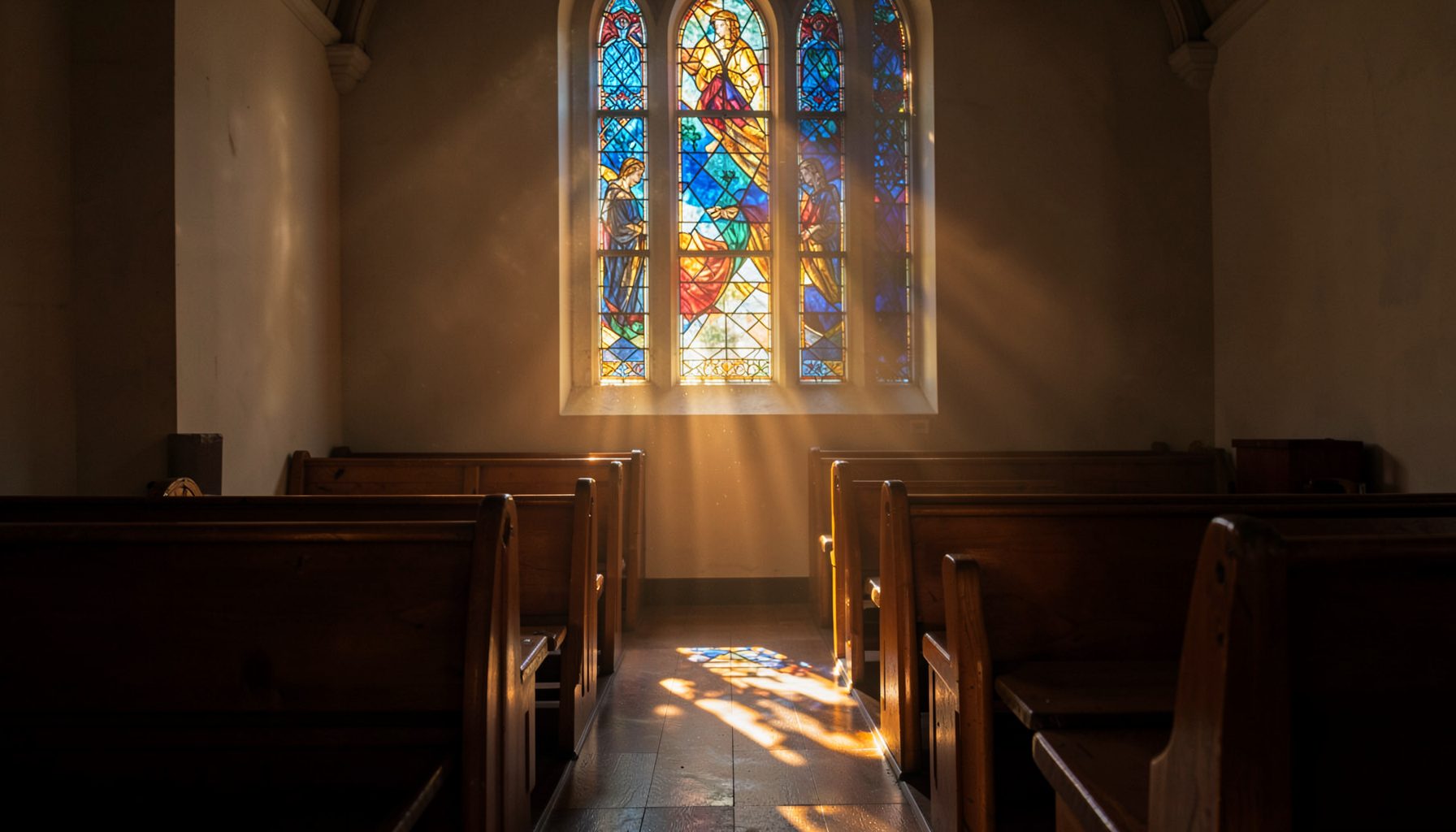Sunlight streaming through a stained-glass window in a quiet sanctuary, casting warm amber and deep blue hues across wooden pews.