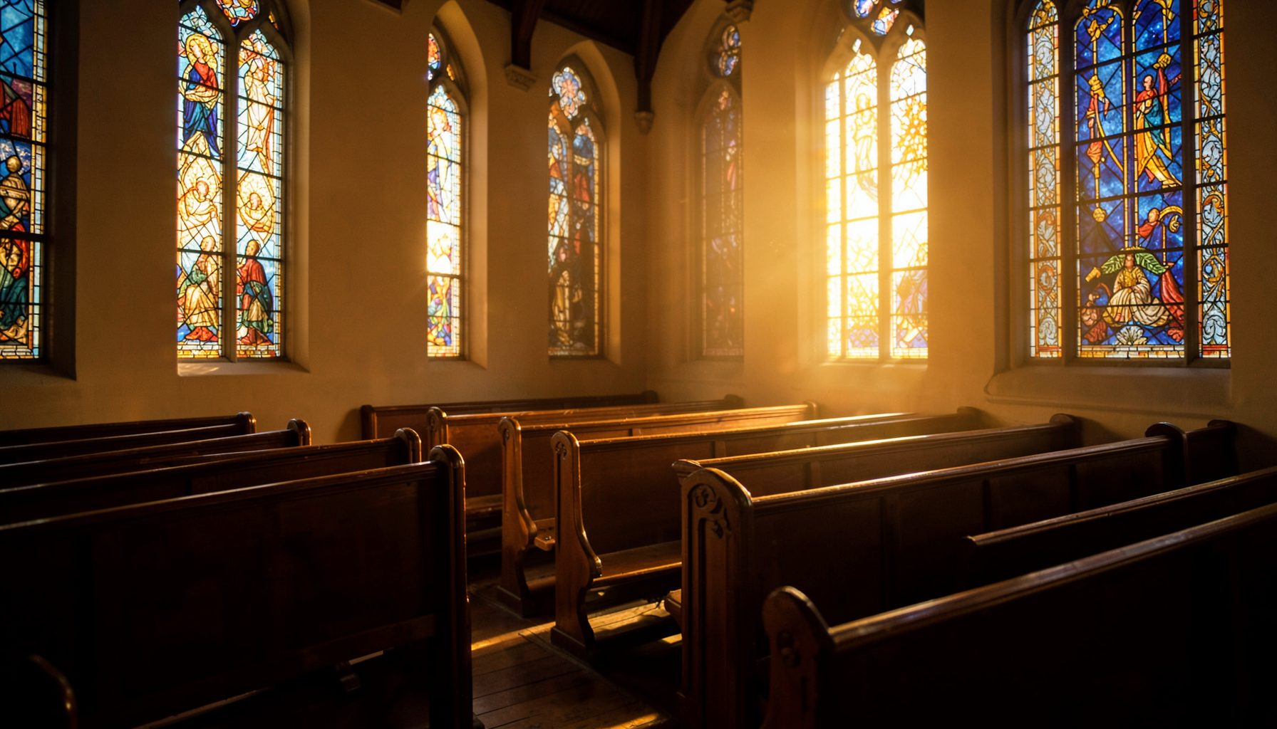 Soft golden light filtering through tall stained-glass style windows onto empty wooden pews, in warm amber and deep blue tones, conveying a calm, reverent mood