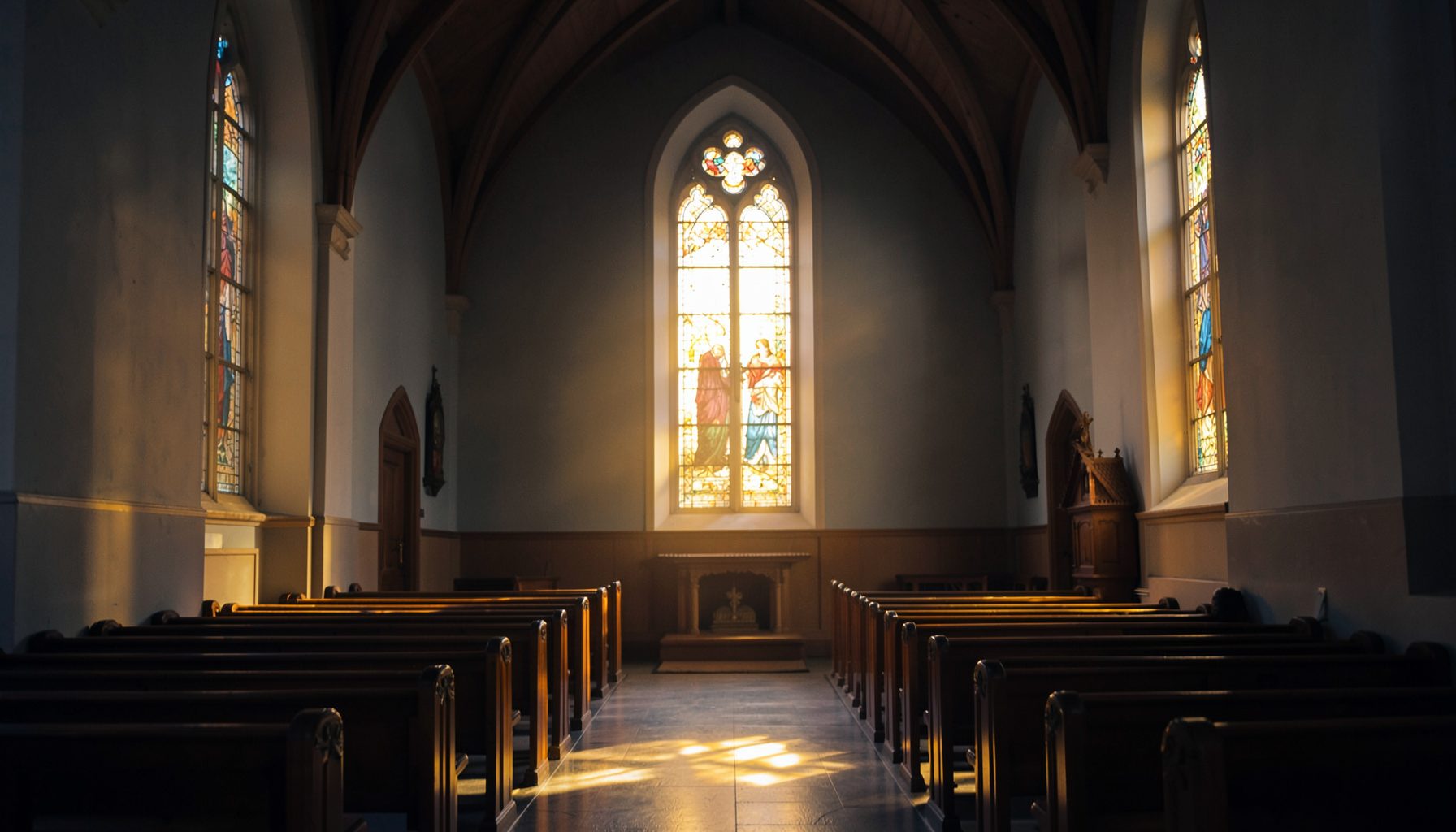 A quiet church interior with warm golden light coming through tall windows, deep blue and amber tones, a calm and reverent mood